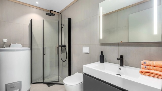 Badet har samme gulvfliser som i gangen og store rektangulære fliser på veggene.