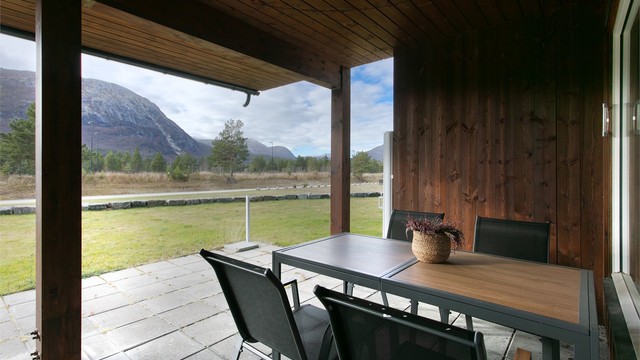Overbygd markterrasse i betongheller med åpent utsyn mot fjellene.