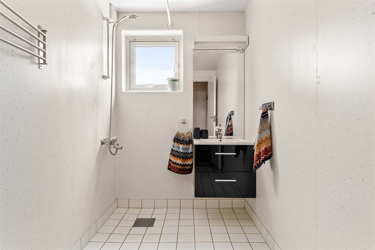 Badet er utstyrt med dusjnisje, servant med underskap og har elektrisk gulvvarme.