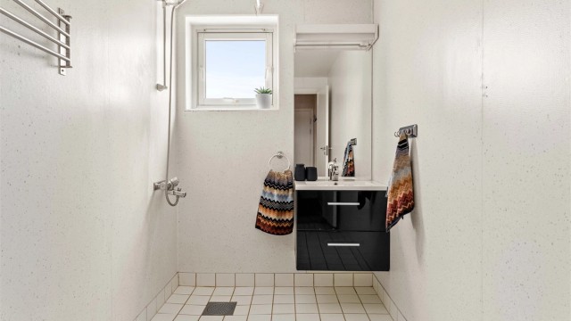 Badet er utstyrt med dusjnisje, servant med underskap og har elektrisk gulvvarme.