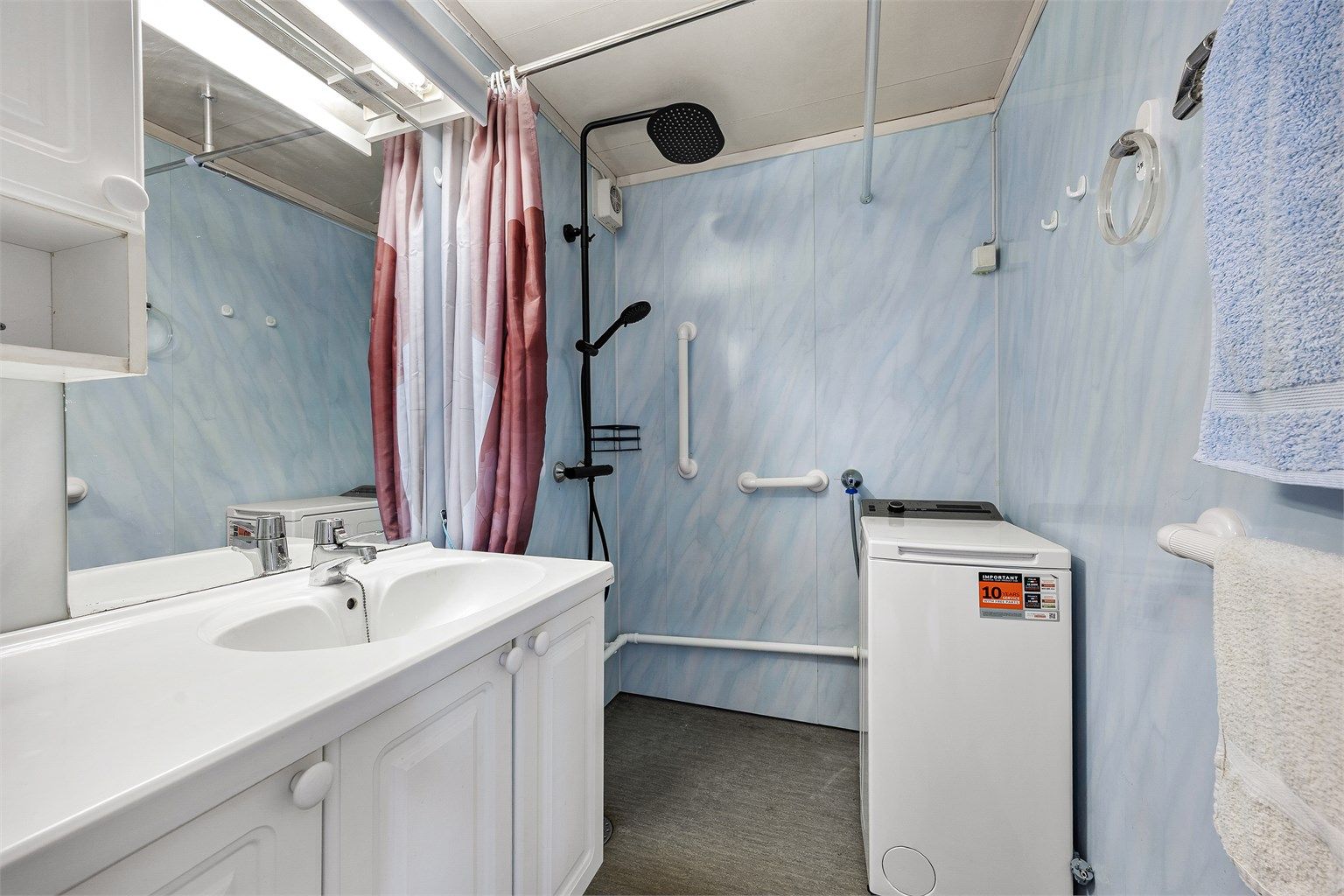 Badet i andre etasje har baderomsplater på veggene, gulvbelegg og opplegg for vaskemaskin.