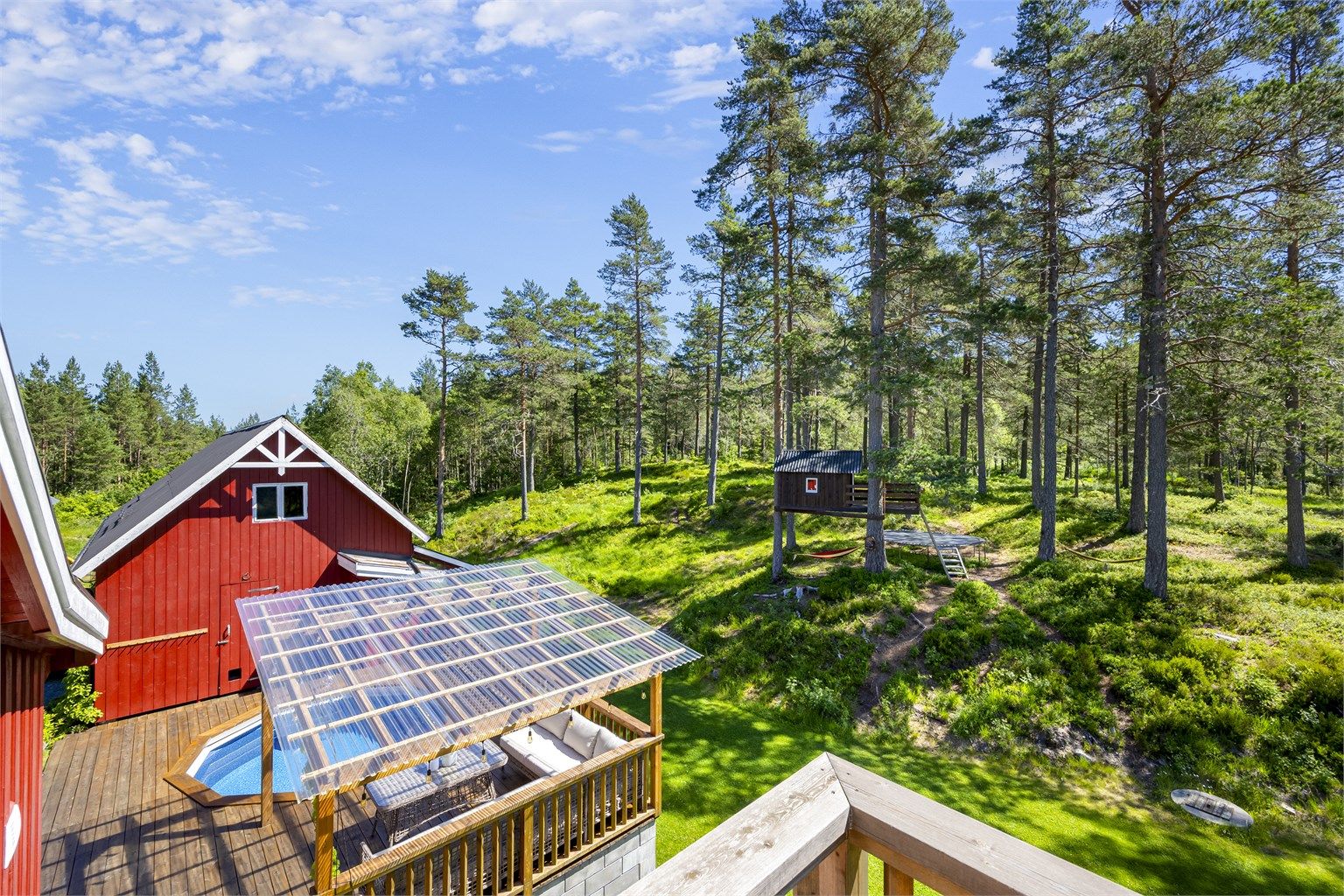 Oversikt over uteområdet med terrasse, basseng og låve.