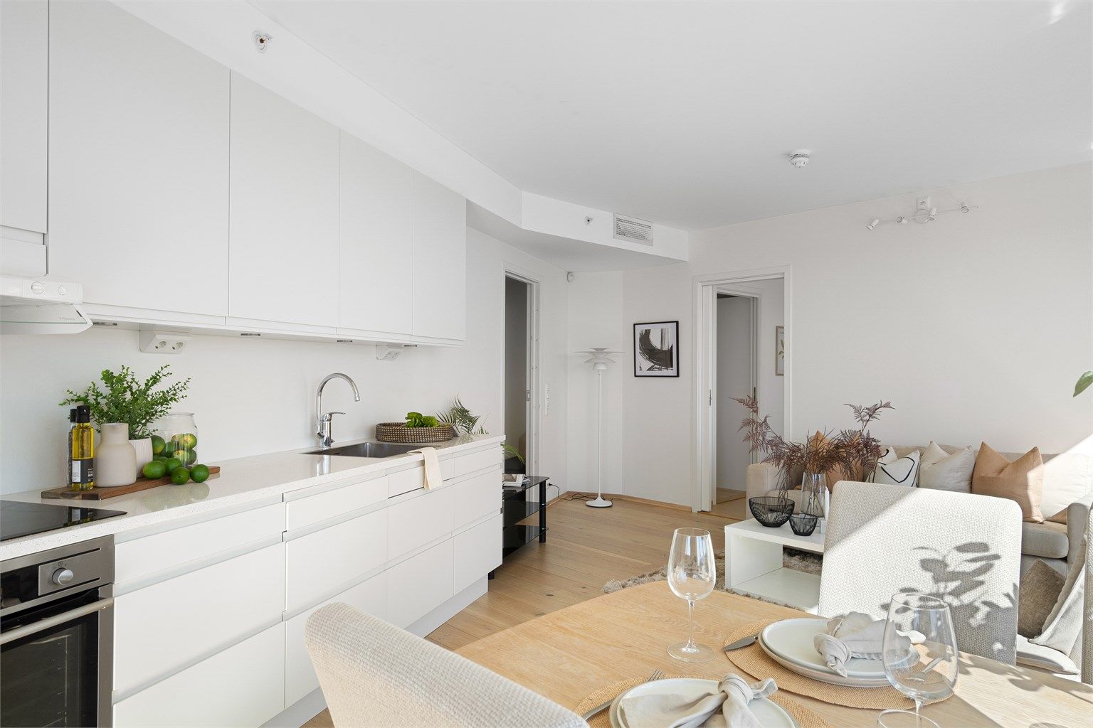 Kjøkkenet er i moderne og fint design med fronter hvitt. Lys benkeplate. Kjøkkeninnredning er fra HTH og det er integrerte hvitevarer, spotter under overskap og bra med benke - og skapplass. Ved kjøkkenet er plass til spisebord. 