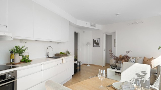 Kjøkkenet er i moderne og fint design med fronter hvitt. Lys benkeplate. Kjøkkeninnredning er fra HTH og det er integrerte hvitevarer, spotter under overskap og bra med benke - og skapplass. Ved kjøkkenet er plass til spisebord.