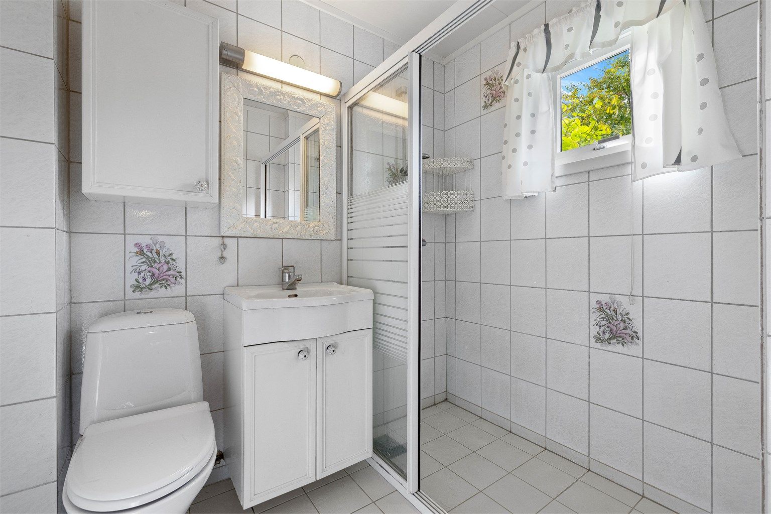 Flislagt bad i 1. etasje med servantinnredning, toalett og dusj med skyvedør i glass.