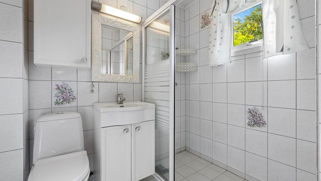 Flislagt bad i 1. etasje med servantinnredning, toalett og dusj med skyvedør i glass.