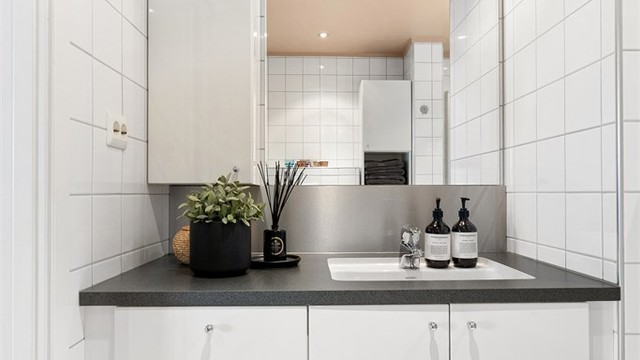 Baderomsinnredning på bad med både skuffer og skap. Speil med overlys og stikkontakt over servant