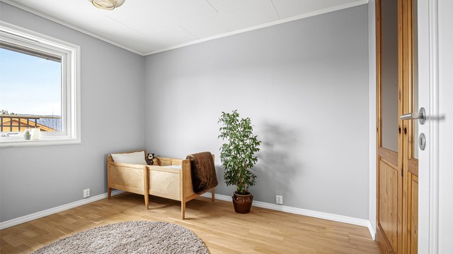 Et av boligens tre soverom, alle med malte flater og profilerte innerdører.