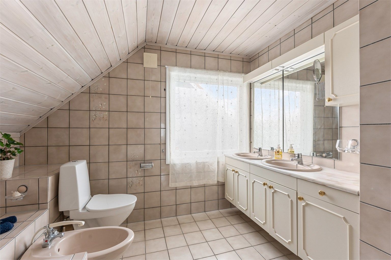 Badet i andre etasje har flislagt gulv med gulvvarme, flislagte vegger og panel i taket.