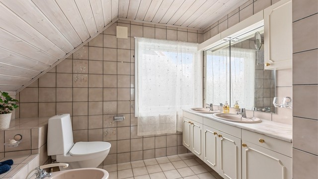 Badet i andre etasje har flislagt gulv med gulvvarme, flislagte vegger og panel i taket.