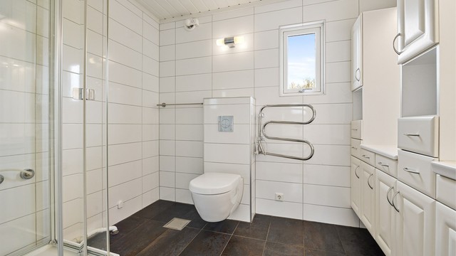Hovedbadet i andre etasje har flislagt gulv med varme, dusjkabinett og vegghengt toalett.