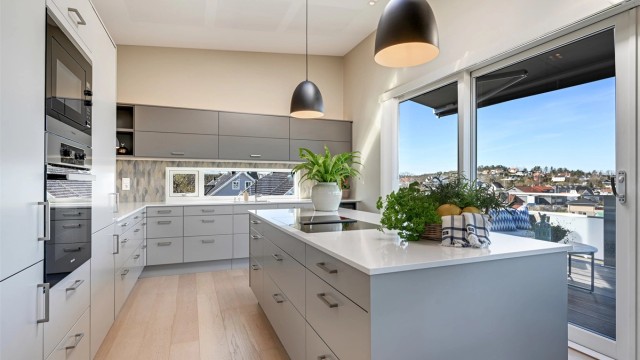 Kjøkkenet i andre etasje har en åpen løsning mot stuen og direkte utgang til en stor balkong via skyvedør i tre/aluminium.