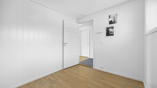 Gjennomgående parkett og malte panelplater på veggene.