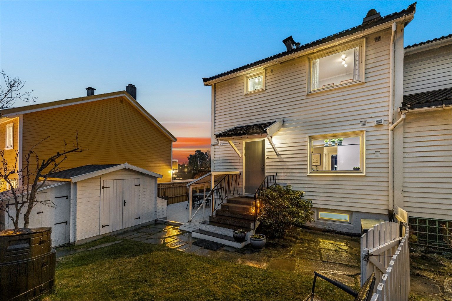 Boligens fasade mot hagen, med inngangspartiet og uteboden.