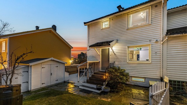 Boligens fasade mot hagen, med inngangspartiet og uteboden.