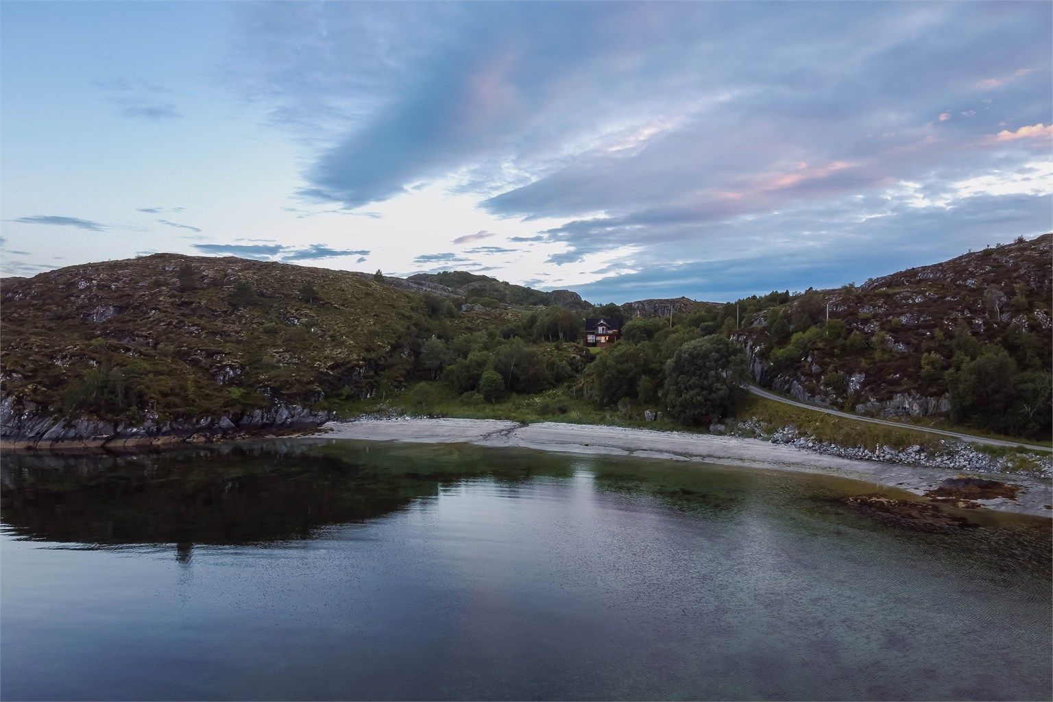 Den nydelige hvite sandstranda strekker seg langs bukta og er en herlig badeplass. Hit er det kort vei både fra huset og brygga