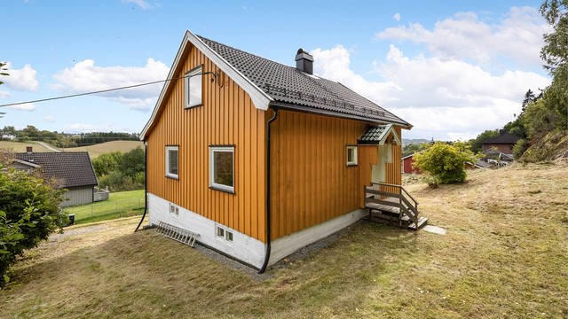 Overbygget inngangsparti med utvendig trapp i tre ved adkomsten i første etasje.