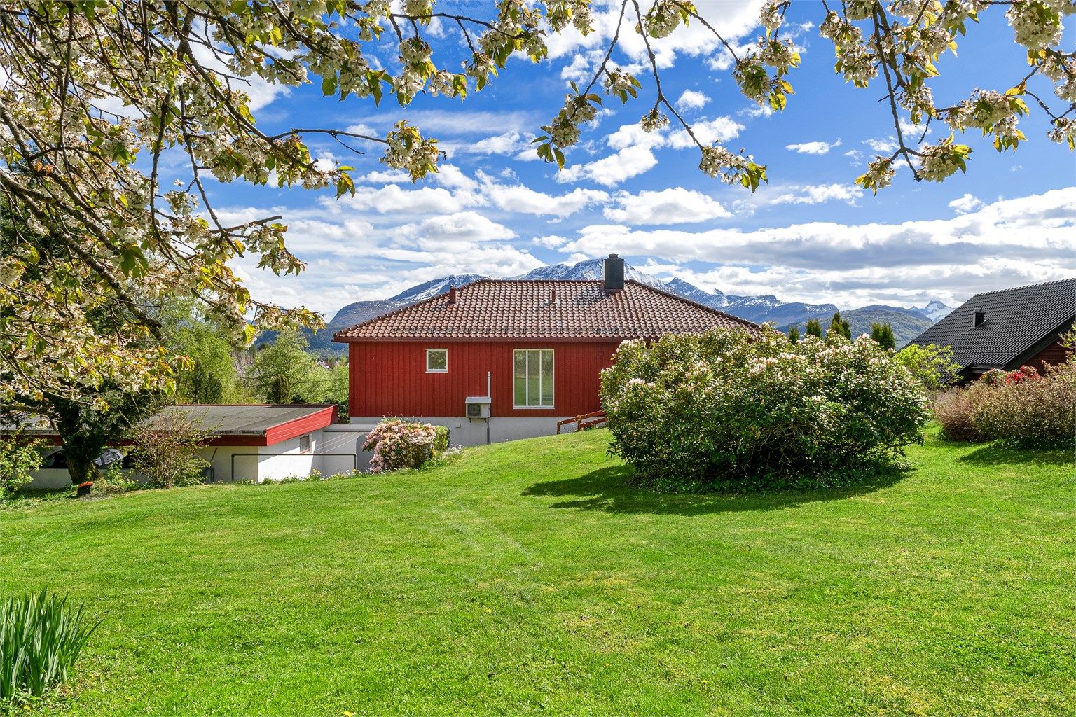På baksiden av huset er det en stor plen og en utvendig bod.