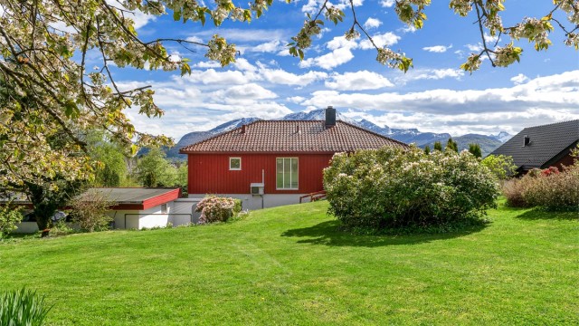 På baksiden av huset er det en stor plen og en utvendig bod.