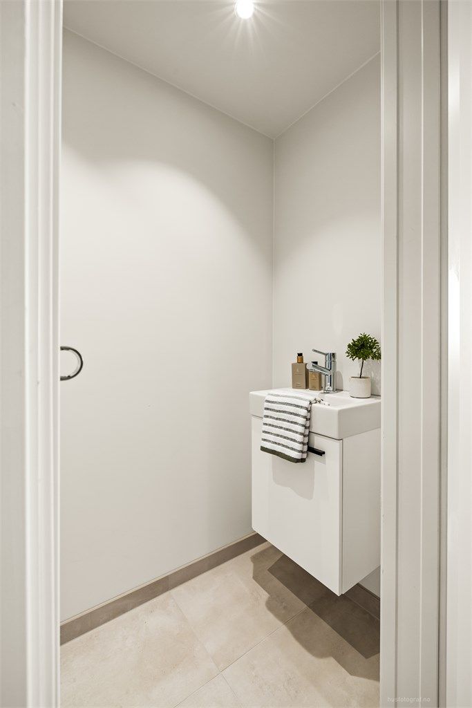 Toalettrommet er utstyrt med vegghengt toalett og servant med innredning.