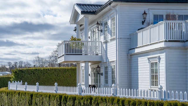 Eiendommen fremstår med et stilrent uttrykk med utebelysning, søyler, glasert takstein og pent opparbeidet hage.