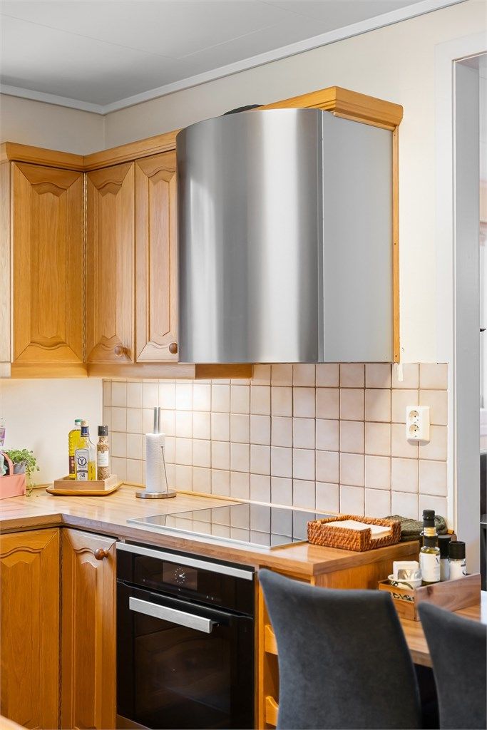 Nedfelt platetopp, komfyr i benk og en vegghengt ventilator i stål.