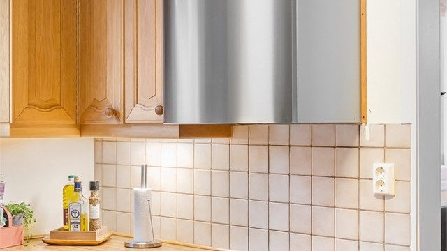 Nedfelt platetopp, komfyr i benk og en vegghengt ventilator i stål.