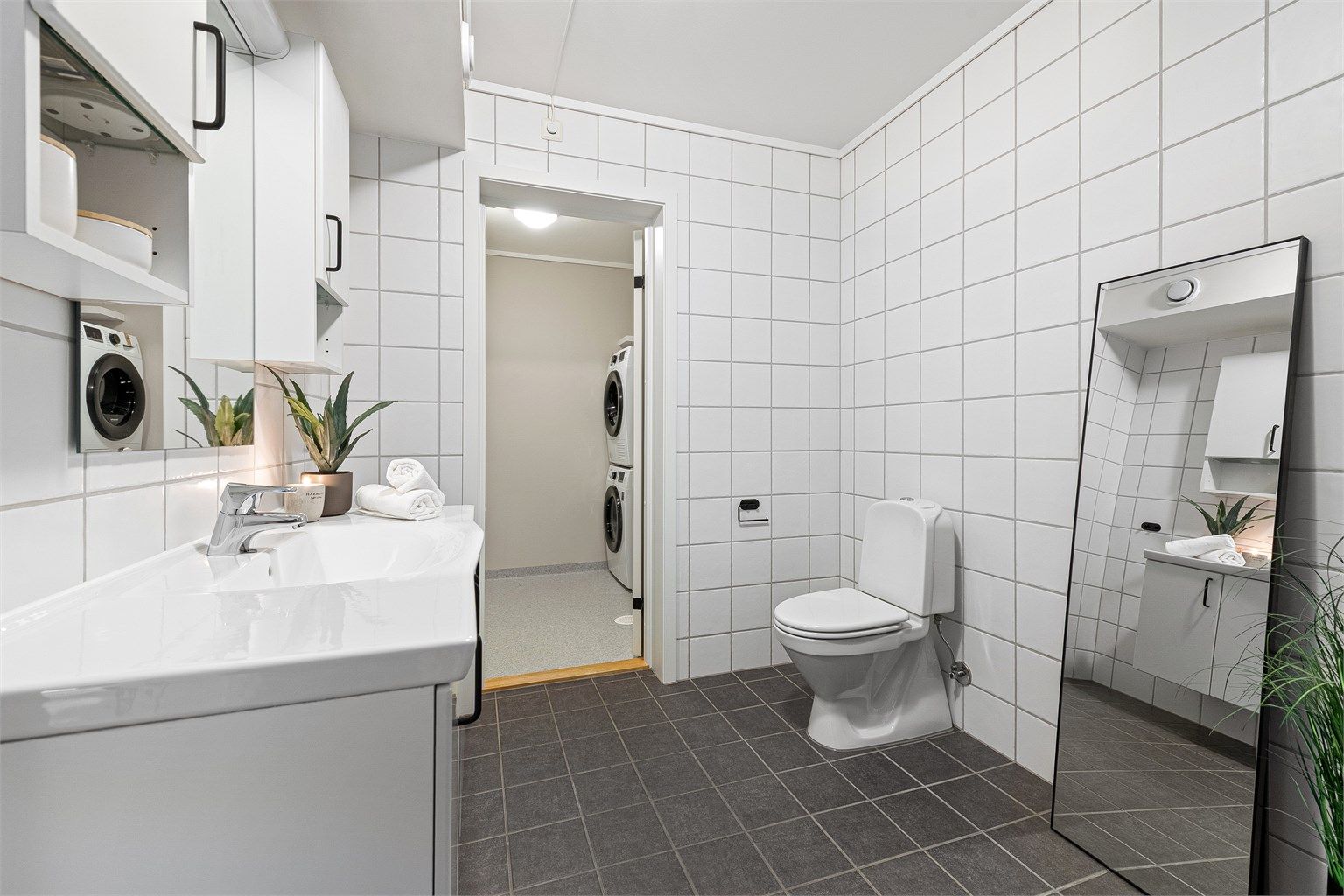 Badet har servantinnredning, gulvstående toalett og adkomst til et praktisk vaskerom.