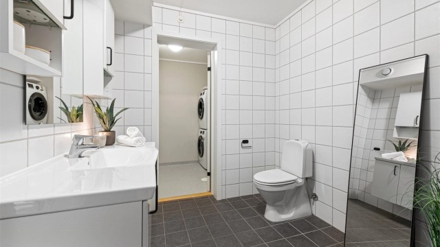 Badet har servantinnredning, gulvstående toalett og adkomst til et praktisk vaskerom.