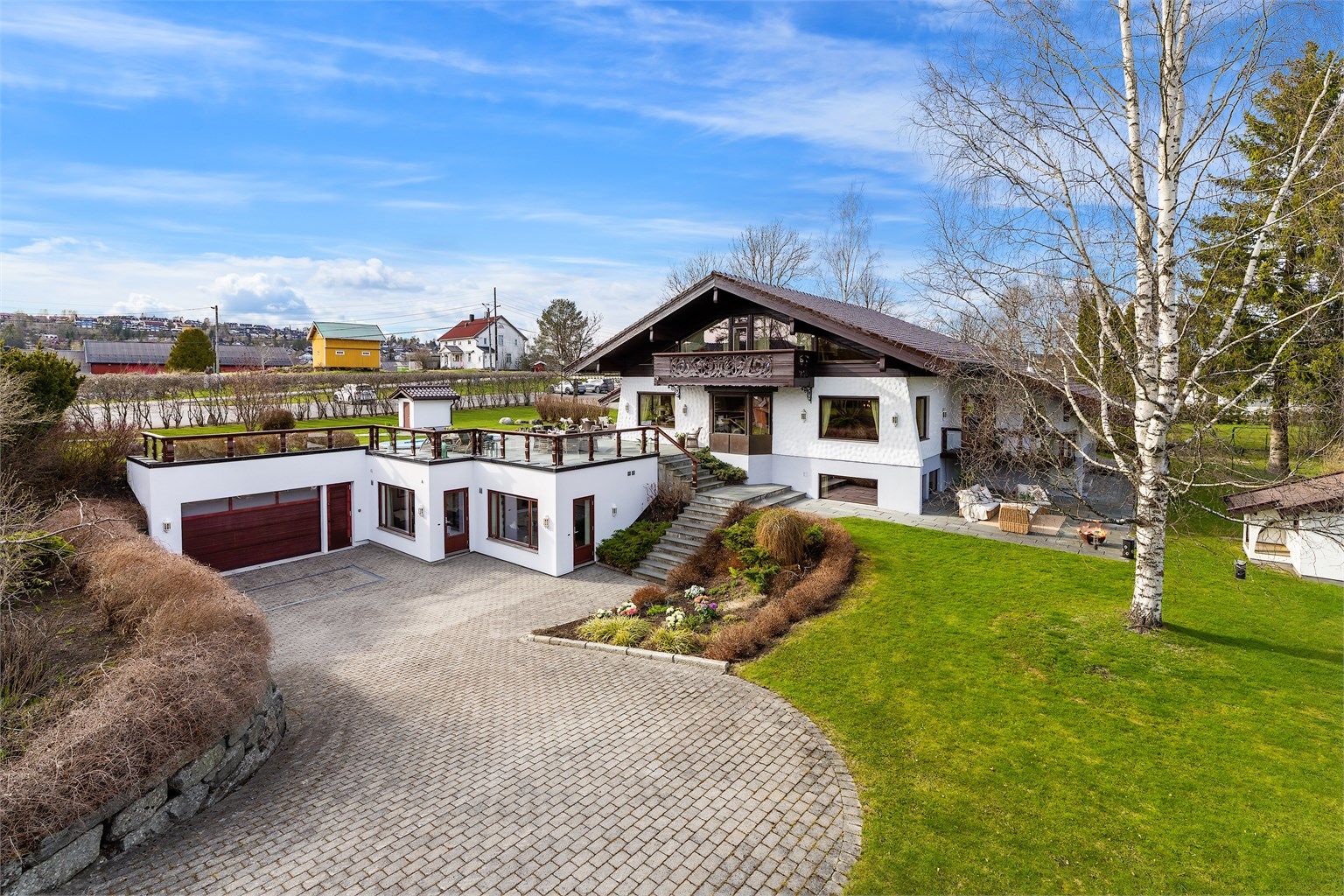 Eiendommen ligger tilbaketrukket på en solrik og parkmessig opparbeidet tomt, hvor frodig beplantning, hellelagte stier og gjennomført utebelysning skaper en harmonisk og representativ ramme. 