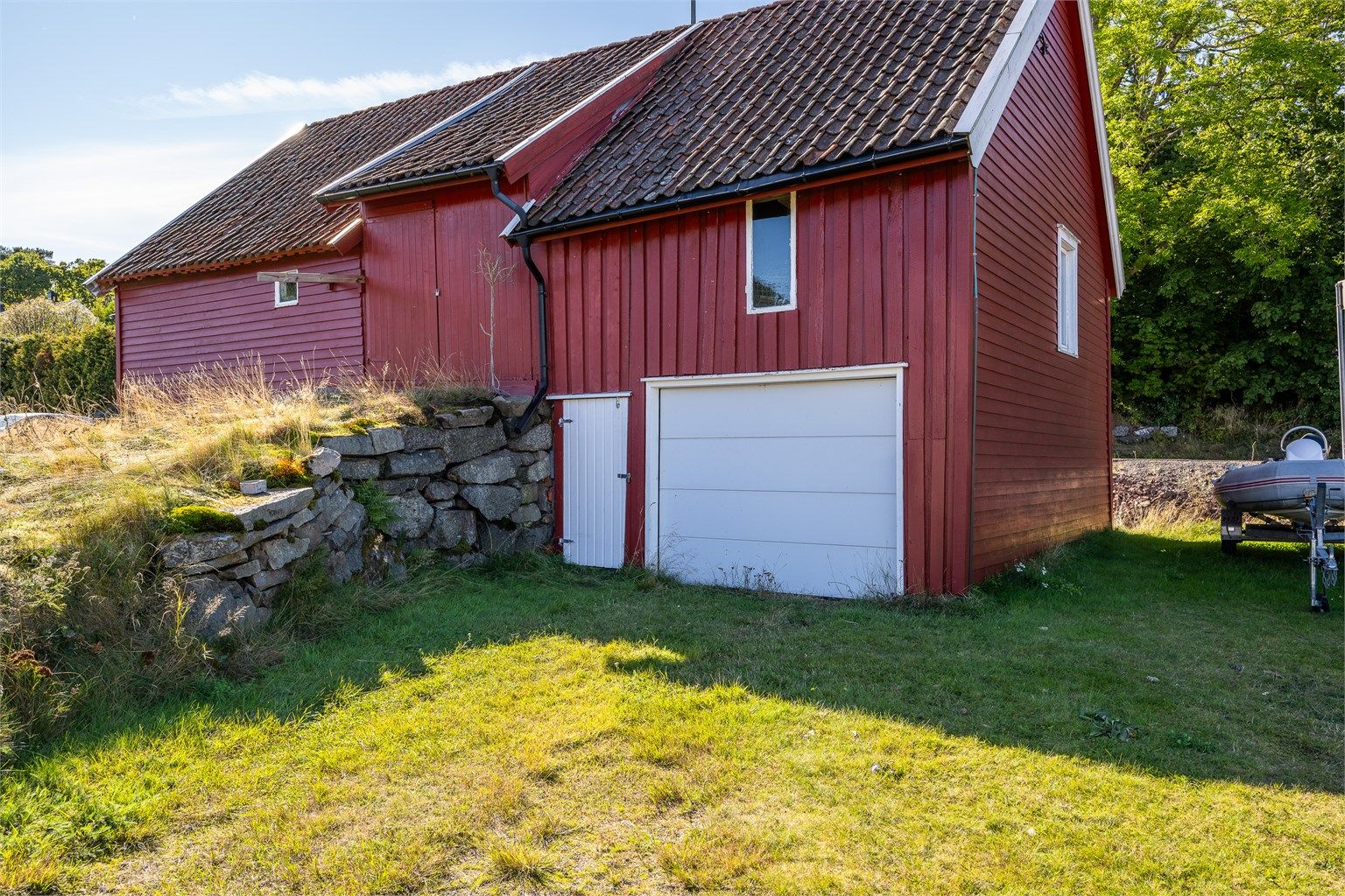 Låven har innkjøring med garasjeport i underetasjen og oppkjøringsrampe til overetasjen.