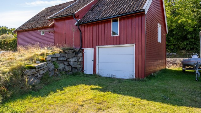 Låven har innkjøring med garasjeport i underetasjen og oppkjøringsrampe til overetasjen.