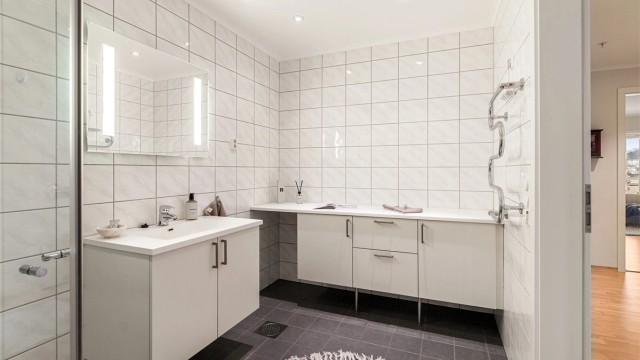 Badet er godt innredet med håndkleholder, servant i innredning, dusjhjørne og toalett. Ekstra skaper med benkeplate for oppbevaring av håndkler etc