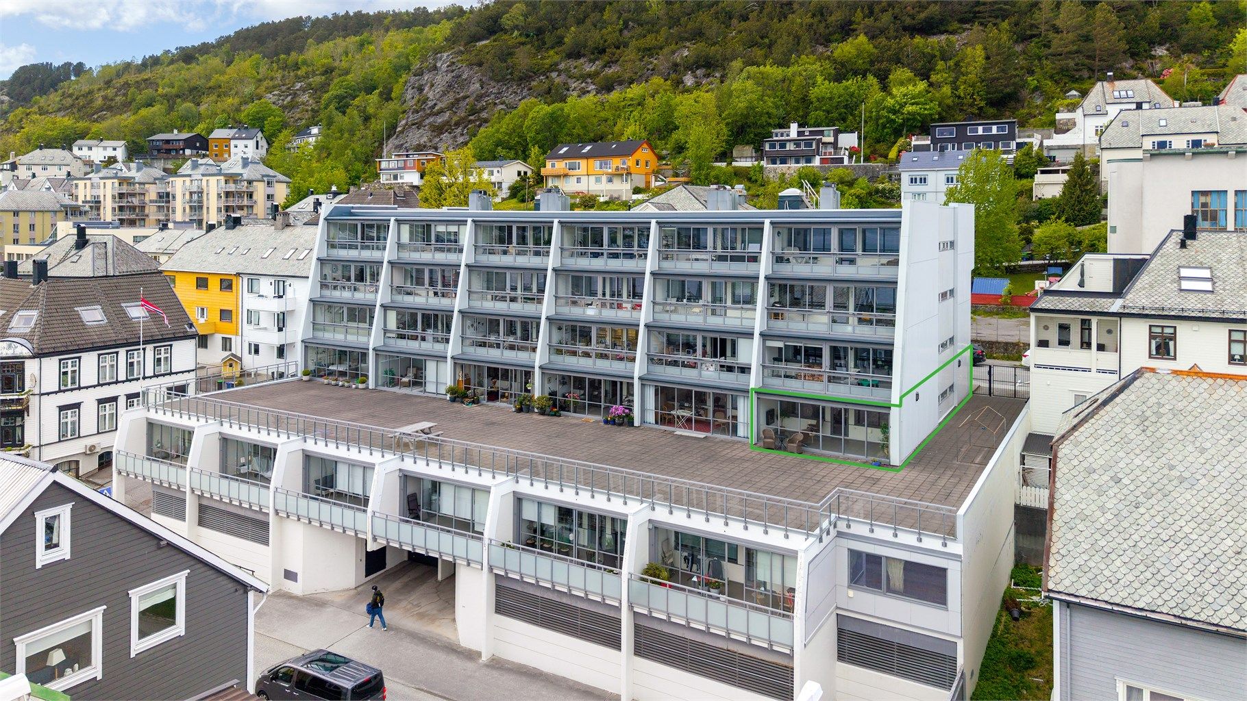 Dronebilde av fasade og leilighetens beliggenhet i 1. etasje på enden mot øst med tilkomst til stor felles terrasse