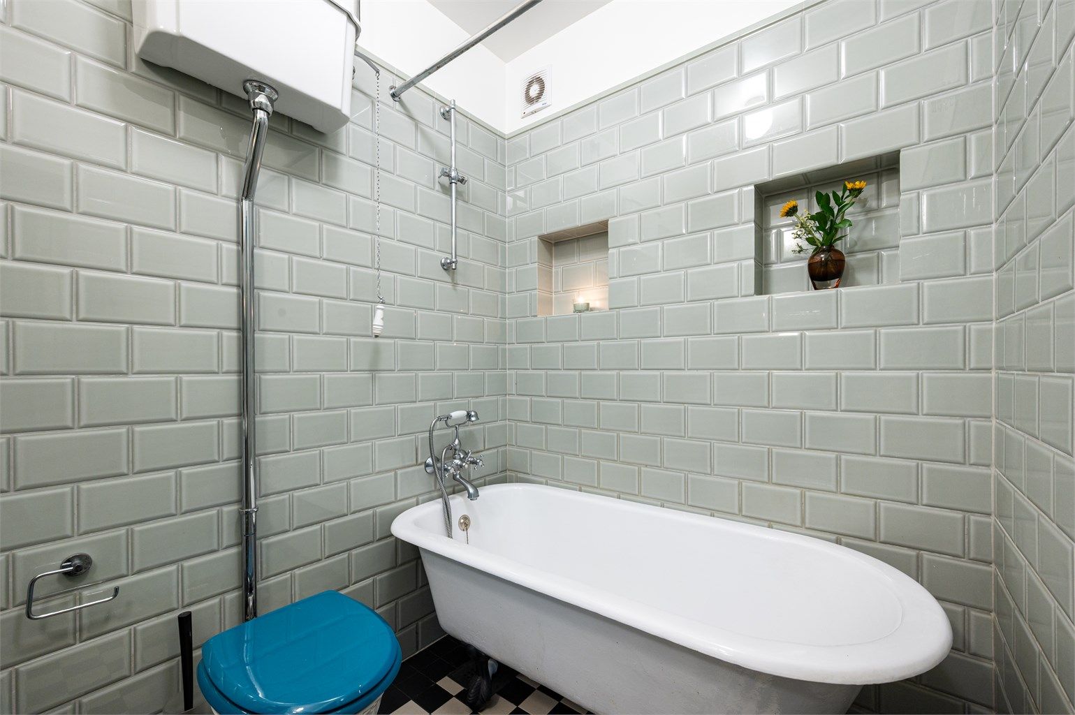 Badet er innredet med gulvstående toalett og badekar som er påkoblet hånddusj. 