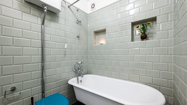 Badet er innredet med gulvstående toalett og badekar som er påkoblet hånddusj.