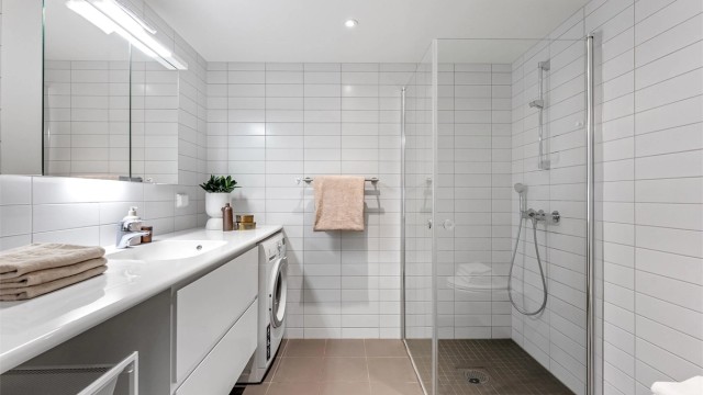 Pent baderom med fliser på gulv med gulvvarme, fliser på vegger og takplater i himling