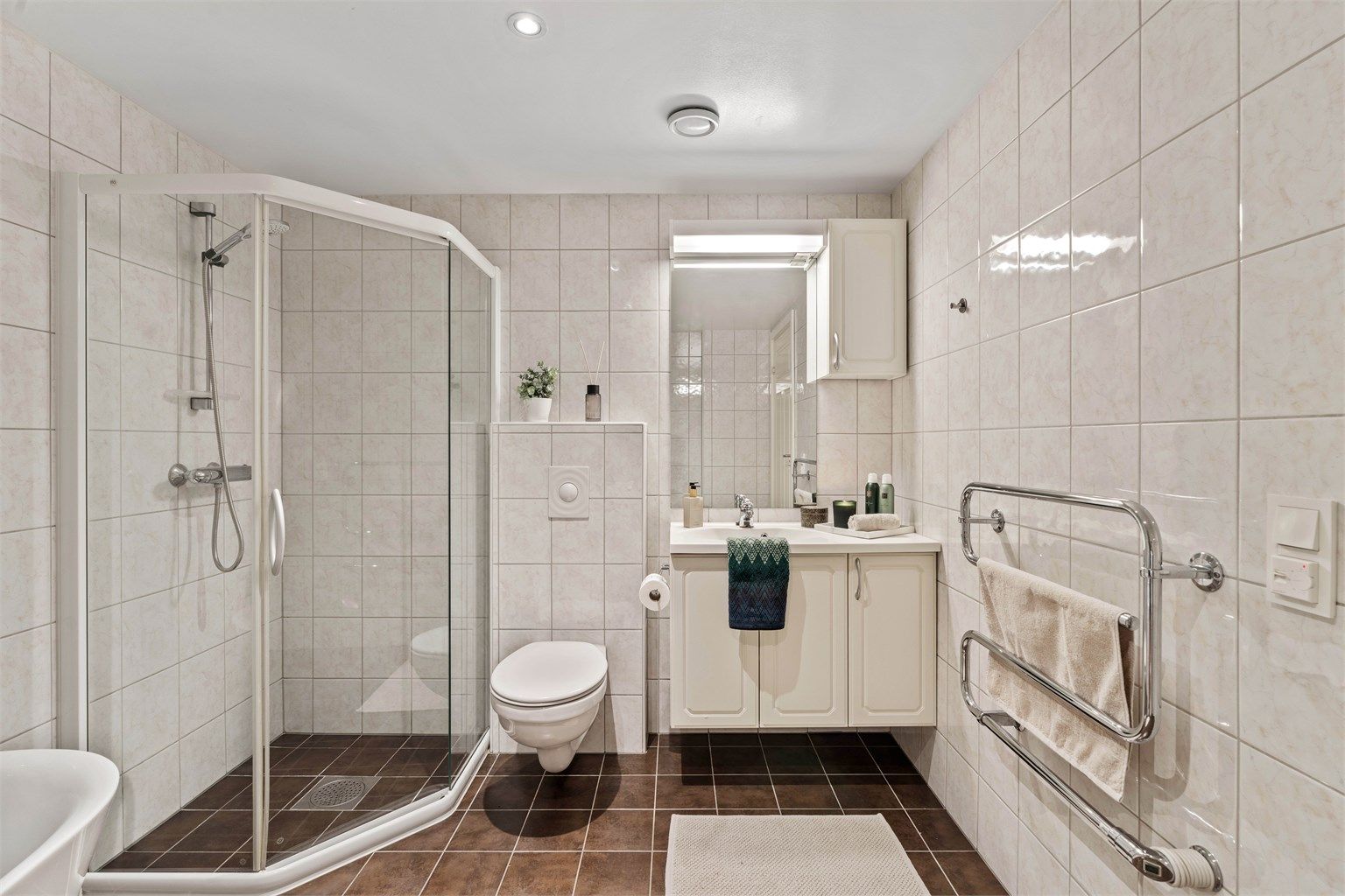 Helfliset bad med gulvvarme, vegghengt toalett og et praktisk dusjhjørne.