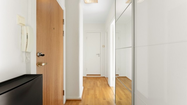 Entré med god plass til oppbevaring i en romslig skyvedørsgarderobe med speilfronter.