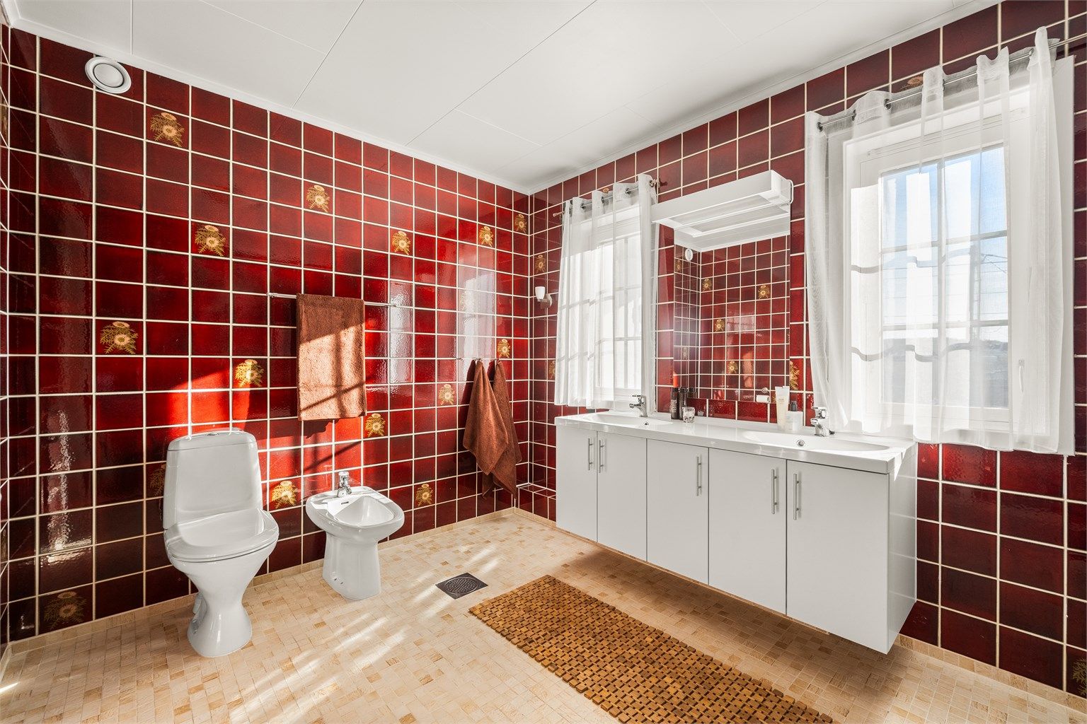 Badet er romslig, med flislagt gulv med gulvvarme, bidet og en bred servantinnredning med doble servanter.