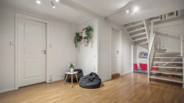En romslig trappegang med praktisk skyvedørsgarderobe gir både plass og orden. Rommet har en åpen og luftig utforming, og selger har valgt å innrede det som en ekstra stue for barna.