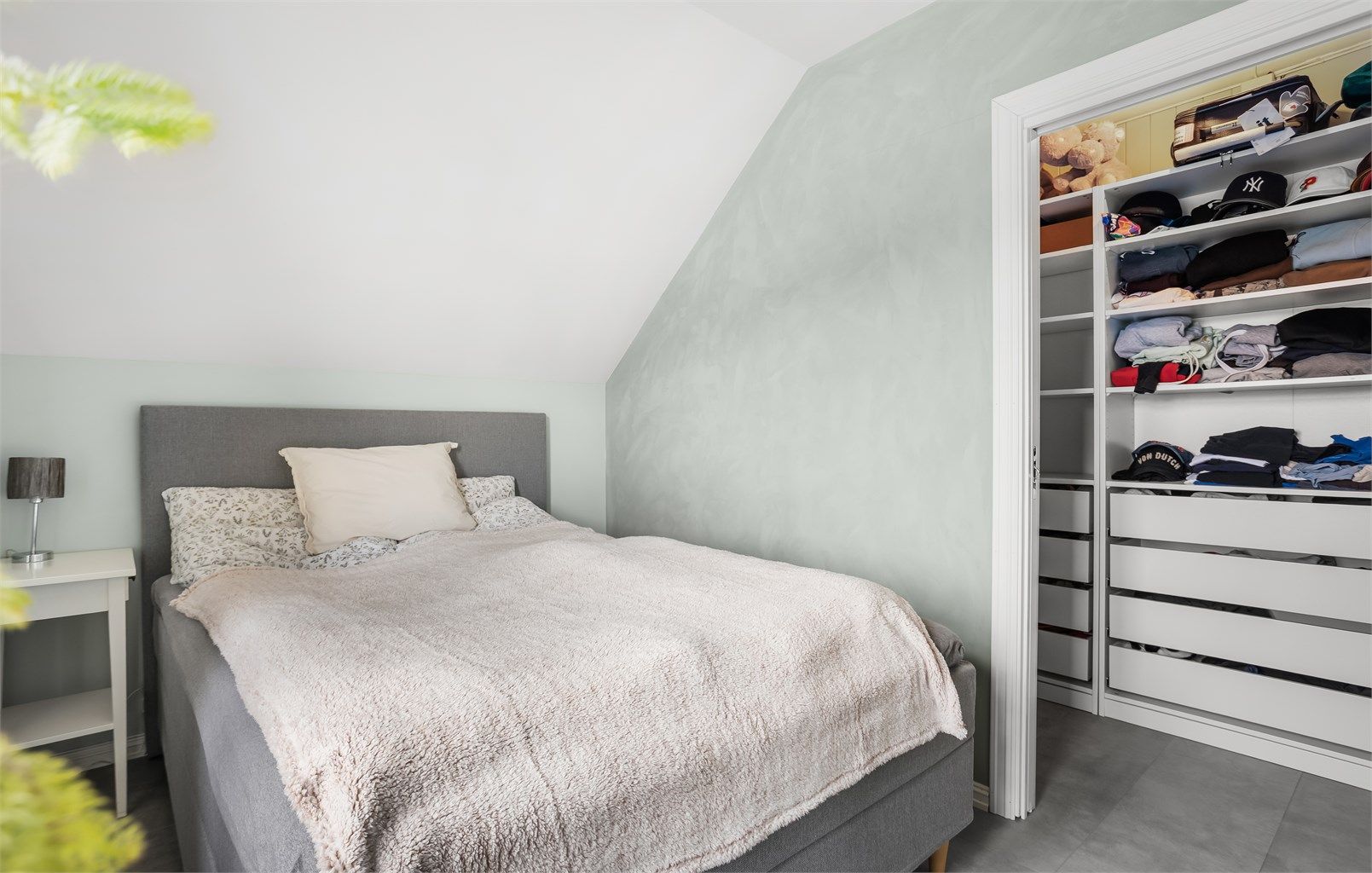 Lunt og innbydende soverom med gode oppbevaringsløsninger i tilknytning til garderobe.