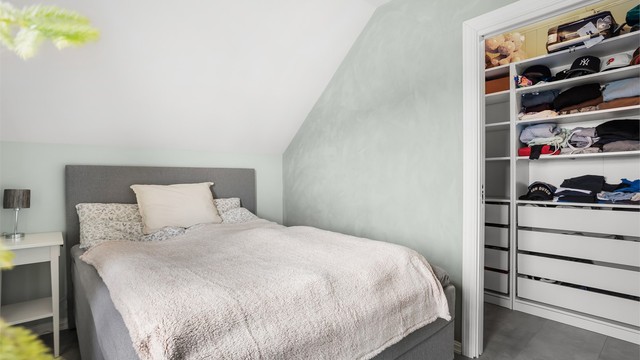 Lunt og innbydende soverom med gode oppbevaringsløsninger i tilknytning til garderobe.