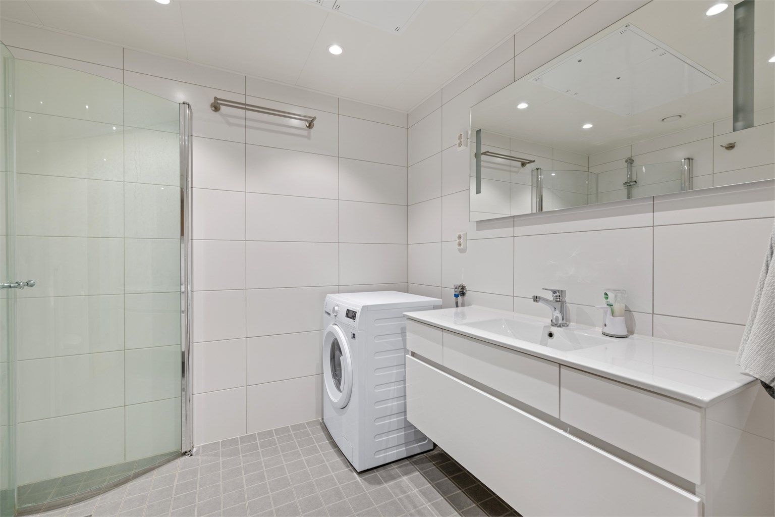 Romslig og lyst bad med plass til både vaskemaskin og tørketrommel. Lun varme i gulvet er behagelig for nakne føtter.