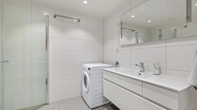 Romslig og lyst bad med plass til både vaskemaskin og tørketrommel. Lun varme i gulvet er behagelig for nakne føtter.