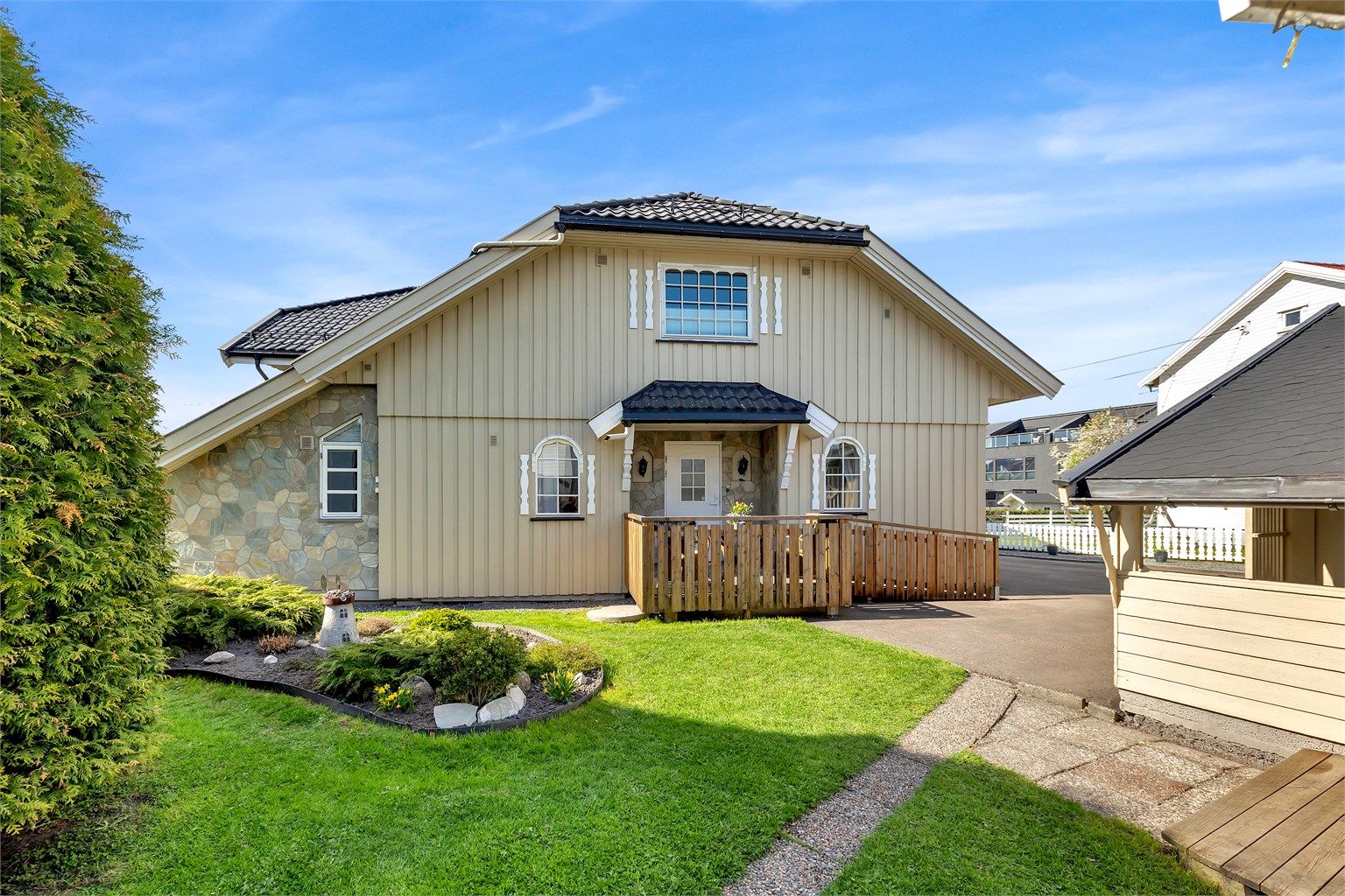 Pent opparbeidet flat tomt med blant annet gressplen, hekk, prydbusker, diverse beplantninger og asfaltert gårdsplass.