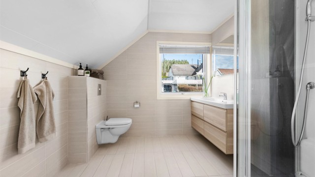 Romslig bad i loftsetasjen, overflateoppusset i ca. 2012. Rommet har gulvvarme og vegghengt toalett