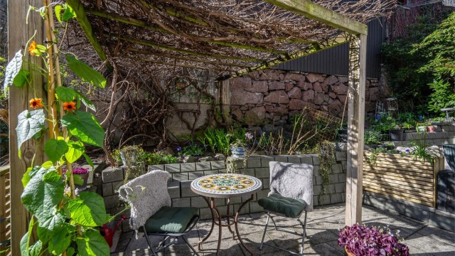 Terrassen er delvis overbygget av en pergola, som gir en hyggelig ramme for uteplassen.