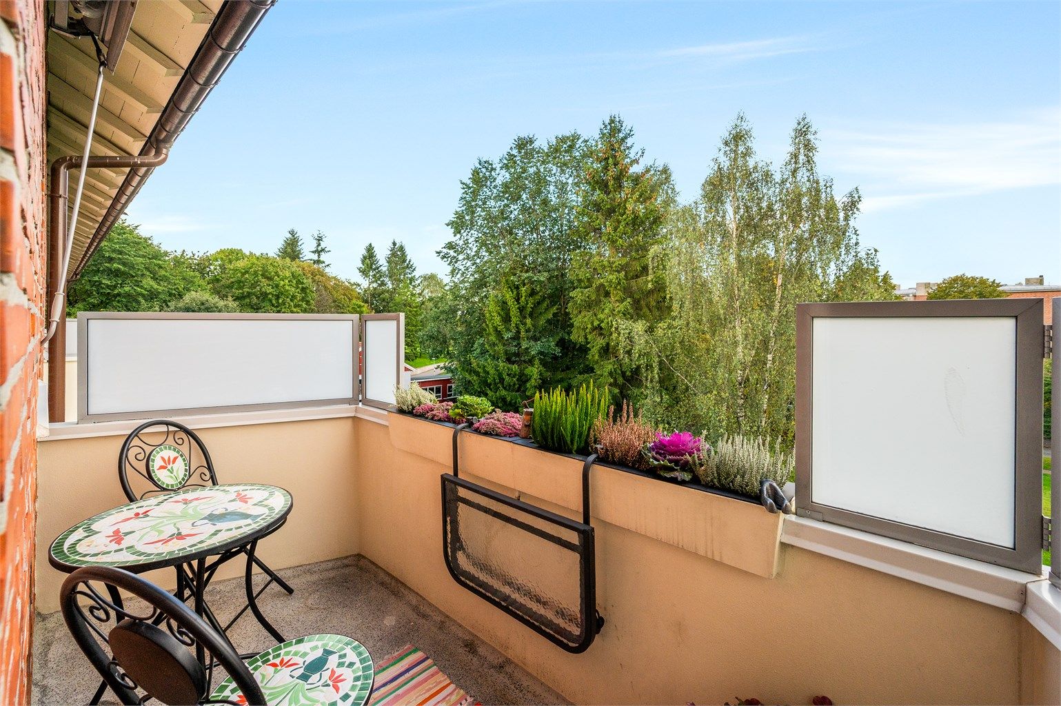 Sydvestvendt balkong med utsyn over park og grønne trær.