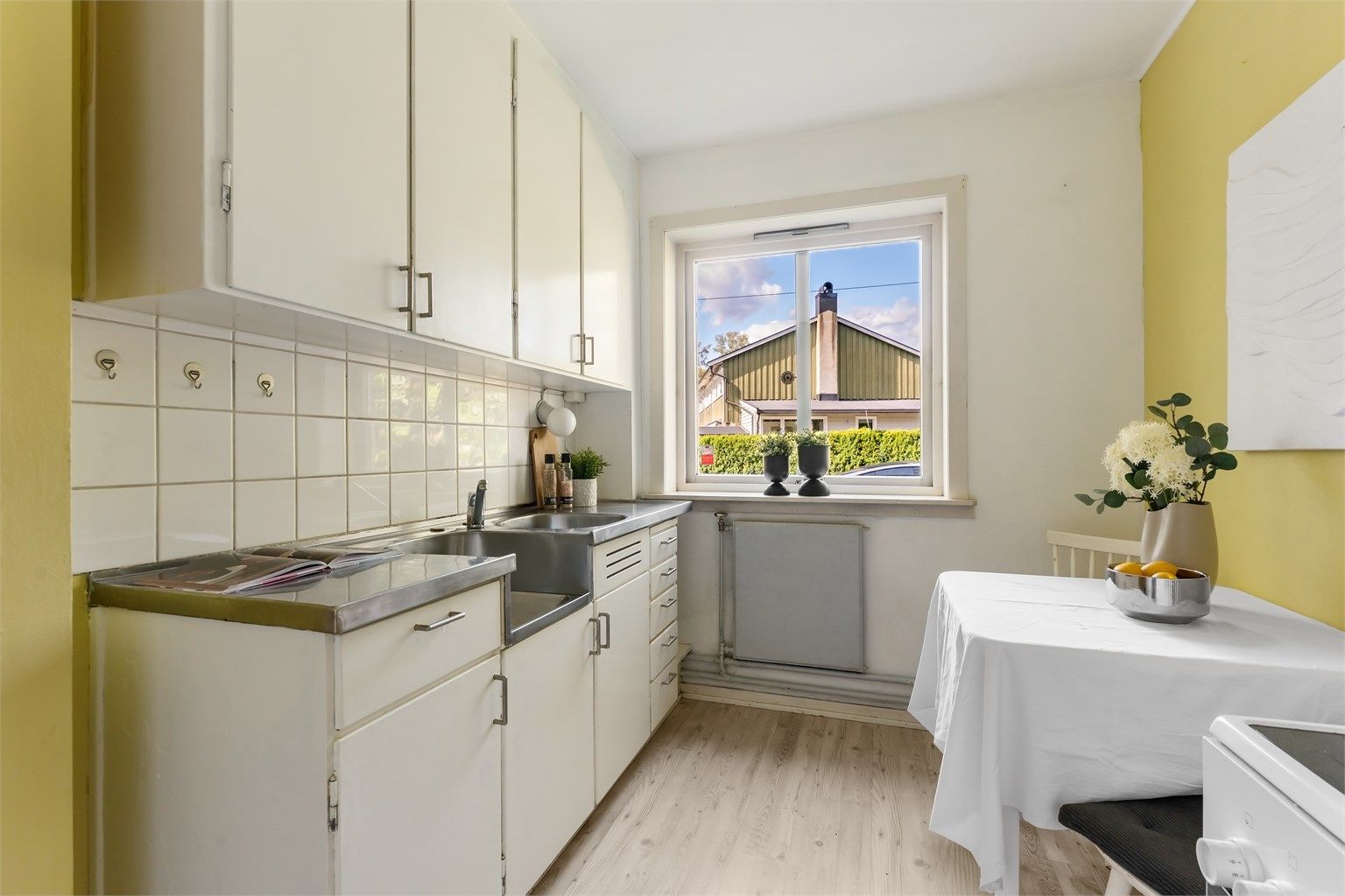 Kjøkkeninnredning med benkeplate i rustfritt stål og fliser over benken.